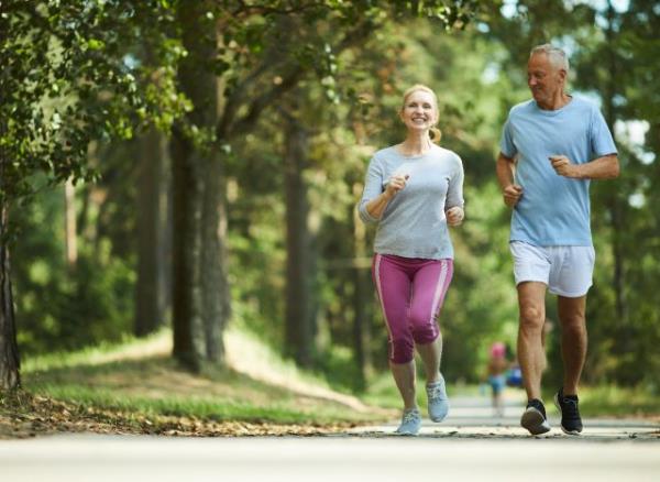 middle-aged couple jogging outdoors, co<em></em>ncept of what's healthier in your 50s walking or jogging